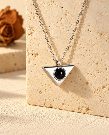 Collana personalizzata argentata a triangolo con foto dentro, appesa a un blocco di travertino