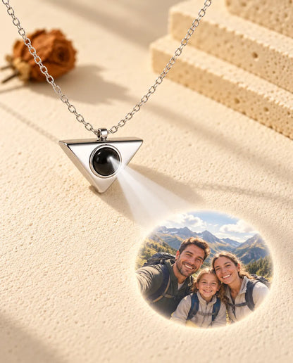 Collana argentata a triangolo che proietta la foto di una famiglia in escursione su intonaco crema