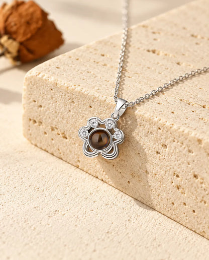 Collana con foto dentro personalizzata a forma di piccola zampa argentata su un blocco di travertino
