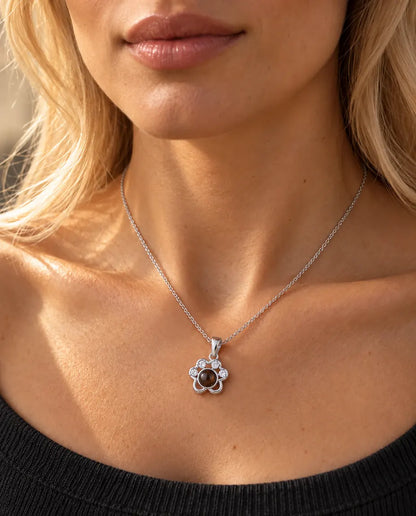 Donna con un top grigio antracite in maglia che indossa la collana a zampa argentata