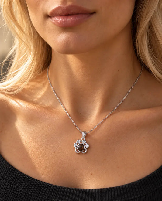 Donna con un top grigio antracite in maglia che indossa la collana a zampa argentata