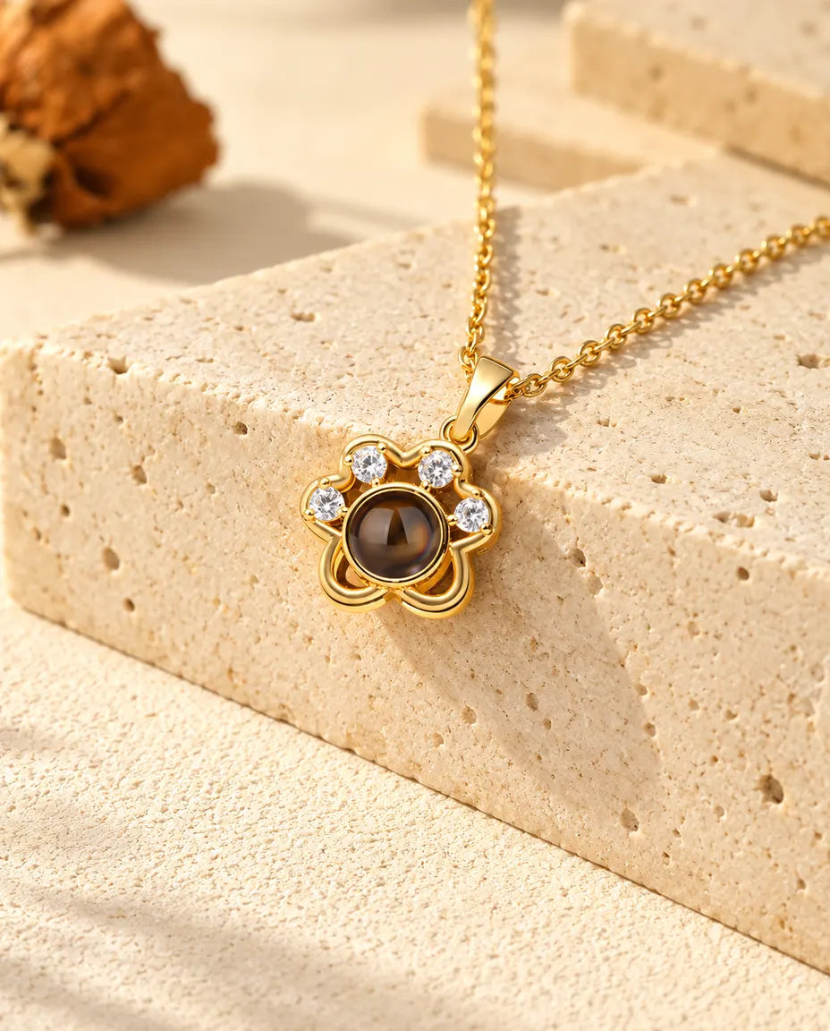Collana a zampa dorata con foto dentro appesa sopra il travertino