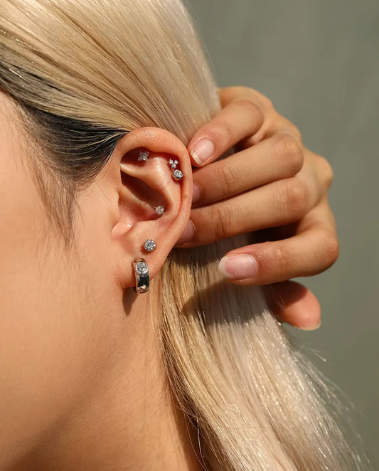 Orecchini a Cerchio Huggie con Moissanite Ovale in Argento 925 - indossato da una modella che sposta i capelli dietro l’orecchio