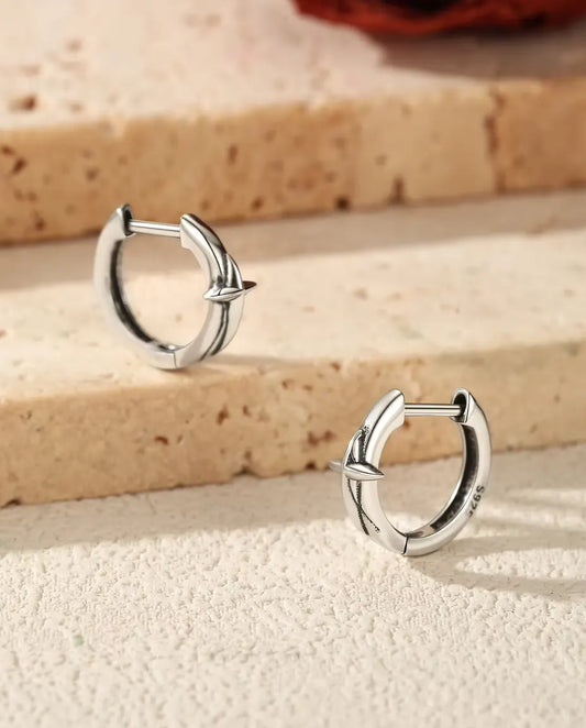 Orecchini a Cerchio Huggie con Stella in Argento 925 - la coppia su gradini di travertino