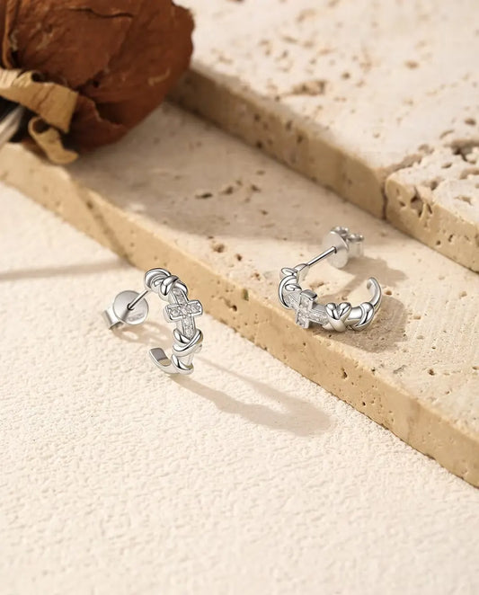 Orecchini a Cerchio Croce Moissanite in Argento 925 - la coppia affiancata su una superficie chiara ruvida
