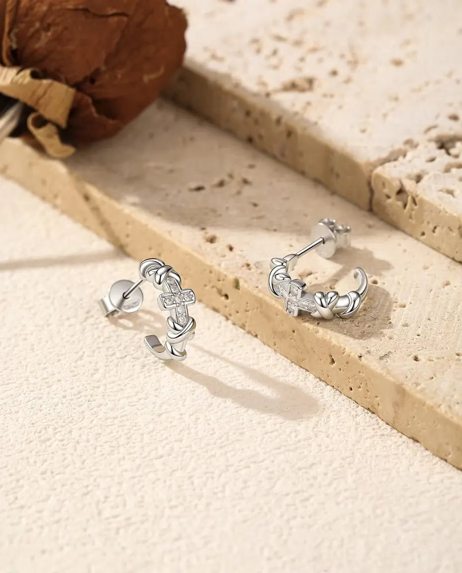Orecchini a Cerchio Croce Moissanite in Argento 925 - la coppia affiancata su una superficie chiara ruvida