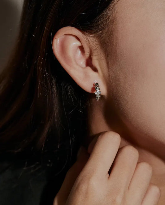 Orecchini a Cerchio Croce Moissanite in Argento 925 - indossati all’orecchio da una modella, mano vicino al viso