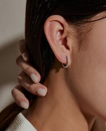 Orecchini a Cerchio Moissanite in Argento 925 - indossati all’orecchio da una modella, mano che tiene indietro i capelli