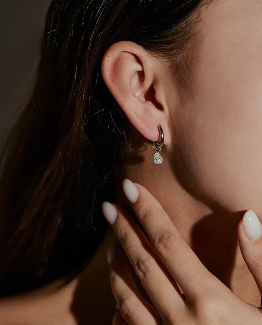 Orecchini a Cerchio Moissanite a Goccia in Argento 925 - indossati all’orecchio da una modella, mano vicino al viso