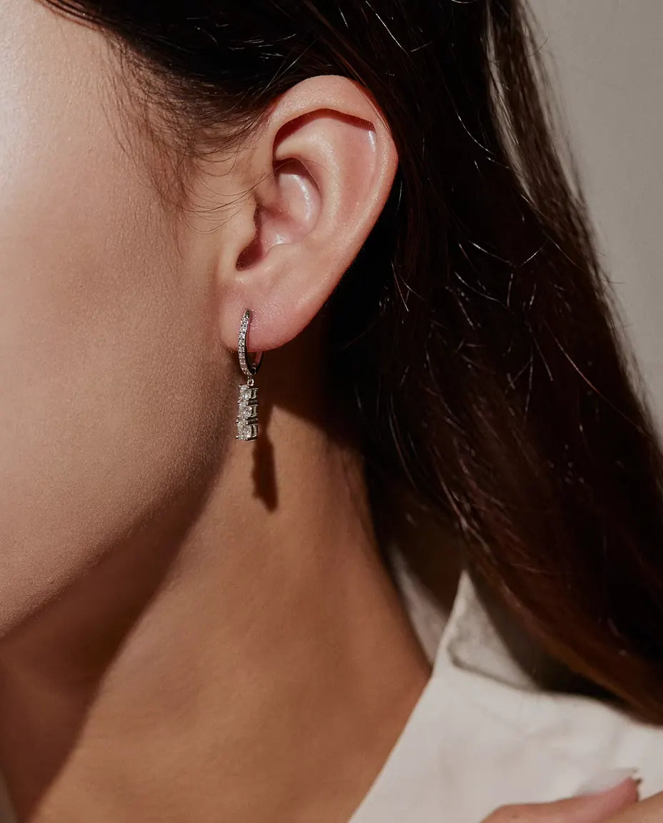 Orecchini a Cerchio Pendenti Moissanite a Tre Pietre in Argento 925 - indossati all’orecchio da una modella, primo piano