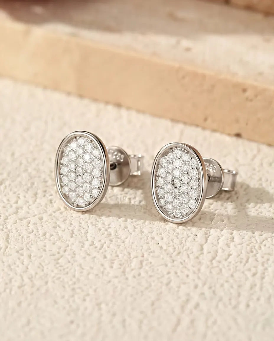 Orecchini Ovali Pavé di Moissanite in Argento 925 - la coppia su una superficie chiara ruvida