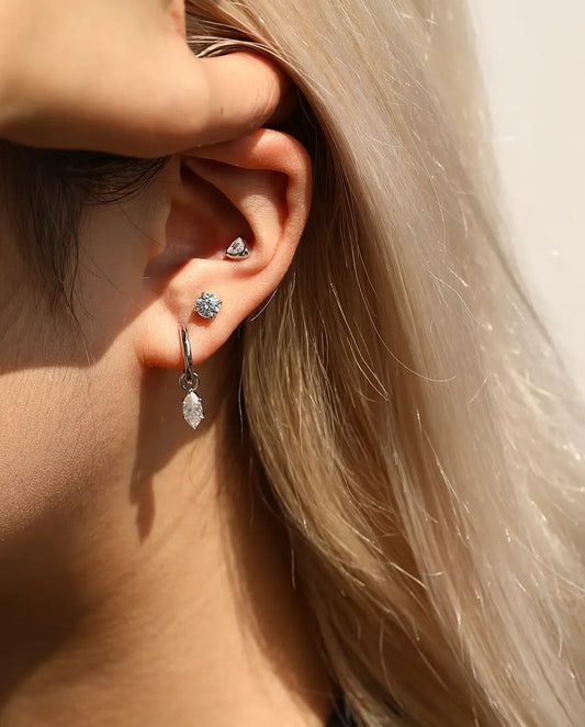 Orecchini Solitario con Moissanite da 5 mm a Quattro Griffe in Argento 925 - indossato da una modella che sposta i capelli dietro l’orecchio