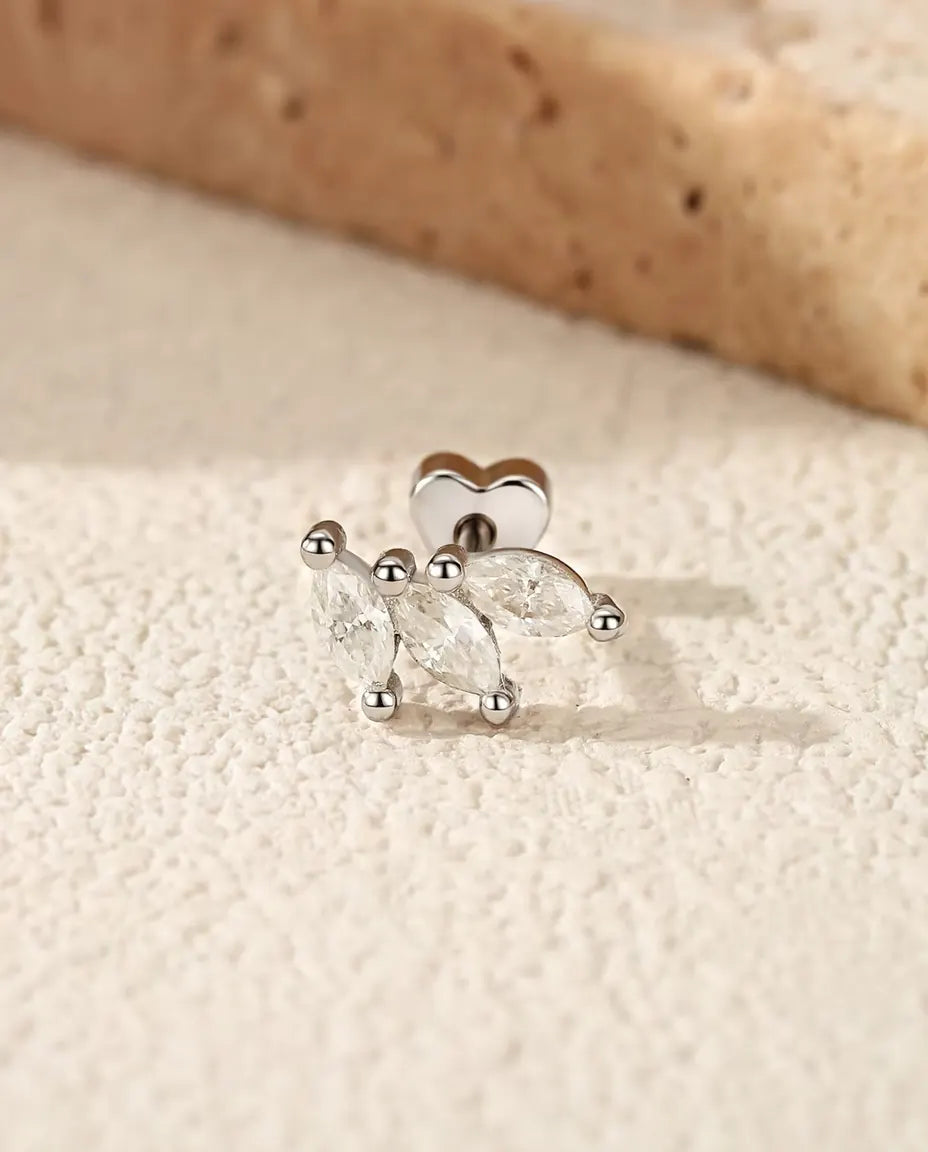 Orecchini a Foglia con Moissanite Marquise in Argento 925 - su una superficie chiara ruvida accanto a una lastra di travertino