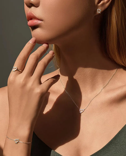Modella che indossa la parure completa con cuore in moissanite: collana, bracciale, anello e orecchini